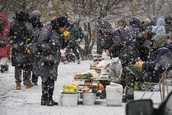 زنی در هنگام بارش برف در سن پترزبورگ از یک فروشنده خیابانی سیب می خرد. سه شنبه 21 نوامبر - اسپوتنیک ایران  