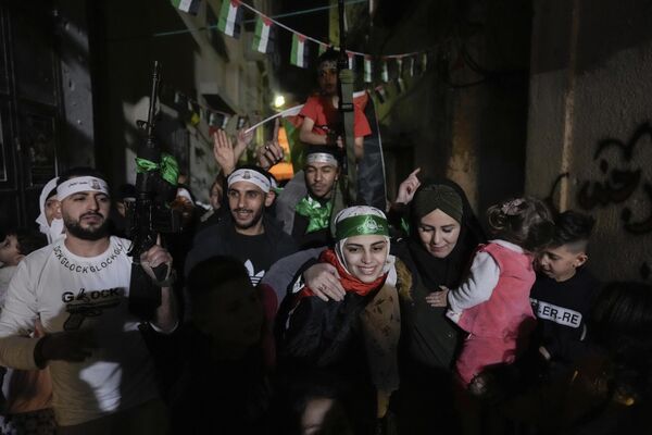 اسیل التیتی با سربند حماس، اسیر فلسطینی سابق که توسط مقامات اسرائیلی آزاد شده بود، در بلطا، اردوگاه آوارگان فلسطینی در نابلس، کرانه باختری، جمعه، 24 نوامبر 2023، مورد استقبال دوستان و اعضای خانواده قرار گرفت. این آزادی در اولین روز از توافق آتش بس چهار روزه بین اسرائیل و حماس صورت گرفت که طی آن شبه نظامیان غزه متعهد شدند 50 گروگان را در ازای 150 فلسطینی زندانی توسط اسرائیل آزاد کنند. (AP Photo/Majdi Mohammed) - اسپوتنیک ایران  