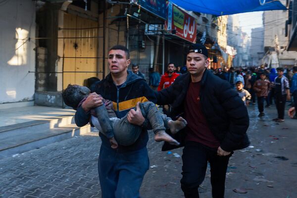 یک فلسطینی پس از بمباران مجدد شهر رفح، در جنوب نوار غزه توسط اسرائیل، پسربچه مجروحی را حمل می کند.آتش بس موقت هفت روزه بین اسرائیل و حماس در اول دسامبر منقضی شد و ارتش اسرائیل اعلام کرد که عملیات جنگی از سر گرفته شده و حماس را به نقض آتش بس متهم کرد. - اسپوتنیک ایران  