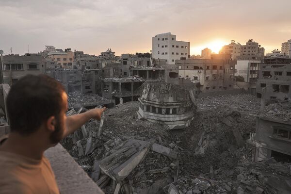 یک فلسطینی به مسجد احمد یاسین اشاره می کند که در اوایل 9 اکتبر 2023 توسط حملات هوایی اسرائیل در شهر غزه با خاک یکسان شد. اسرائیل بی امان نوار غزه را در طول شب و روز 9 اکتبر در حالی که درگیری با حماس در اطراف نوار غزه ادامه داشت، بمباران می کرد. تلفات جنگ علیه مبارزان فلسطینی به بیش از 1100 افزایش یافت. - اسپوتنیک ایران  