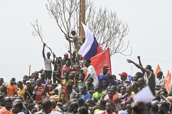 مردم با بلند کردن پرچم‌های ملی روسیه به عنوان حامیان شورای ملی حفاظت از وطن نیجر در خارج از پایگاه هوایی نیجر و فرانسه در نیامی در 2 سپتامبر 2023 برای درخواست خروج ارتش فرانسه از نیجر تظاهرات کردند. - اسپوتنیک ایران  