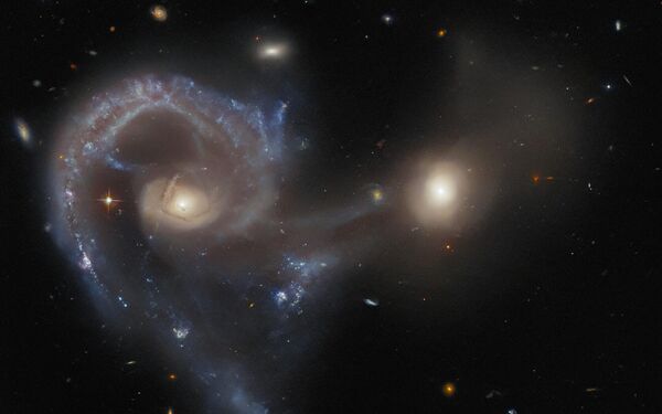 این عکس که با استفاده از دوربین پیشرفته تلسکوپ فضایی هابل گرفته شده است - Arp 107 را نشان می دهد، یک جرم آسمانی که شامل یک جفت کهکشان در میانه یک برخورد است. کهکشان بزرگتر (در سمت چپ این تصویر) یک نوع کهکشان بسیار پرانرژی است که به نام کهکشان سیفرت شناخته می شود که هسته های کهکشانی فعال را در هسته خود جای می دهد. کهکشان های سیفرت قابل توجه هستند زیرا علیرغم روشنایی بسیار زیاد هسته فعال، تابش آنها از کل کهکشان قابل مشاهده است. - اسپوتنیک ایران  
