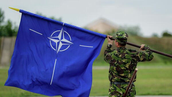 A Romanian serviceman furls the NATO flag. File photo - اسپوتنیک ایران  