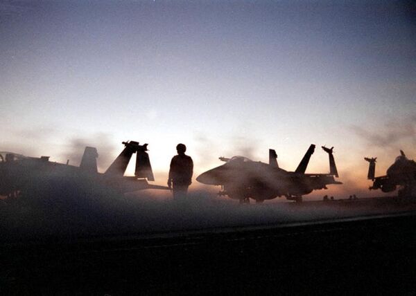 خورشید بر فراز هواپیمای USS Enterprise غروب می کند و خدمه در 19 دسامبر 1998 آماده می شوند تا موج چهارم حملات هوایی علیه عراق را در طی عملیات روباه صحرا انجام دهند. - اسپوتنیک ایران  