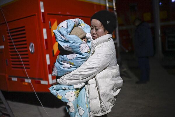 یک زن پس از زلزله در شعر داهجیا، شهرستان جیشیشان در استان گانسو شمال غربی چین در 19 دسامبر 2023، کودکی را در خیابانی در آغوش دارد. - اسپوتنیک ایران  