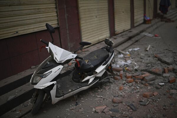 یک اسکوتر و آوار ها در خیابانی پس از زلزله در داهجیا، شهرستان جیشیشان در استان گانسو شمال غربی چین در 19 دسامبر 2023 دیده می شود. - اسپوتنیک ایران  