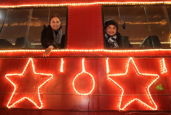 مردم در ایستگاه قطار «اوساکیون» در قطار سابانا که با چراغ های کریسمس تزئین شده است، عکس می گیرند. - اسپوتنیک ایران  