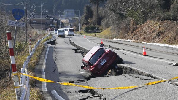 یک خودرو در یک جاده نیمه فرو ریخته ناشی از زلزله قوی در نزدیکی شهر آنامیزو در استان ایشیکاوا ژاپن گیر کرده است. - اسپوتنیک ایران  