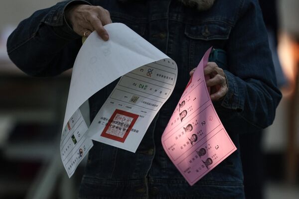 فردی برگه های رای گیری را در یک شعبه رای گیری در دبیرستانی در تاینان در دست دارد. - اسپوتنیک ایران  