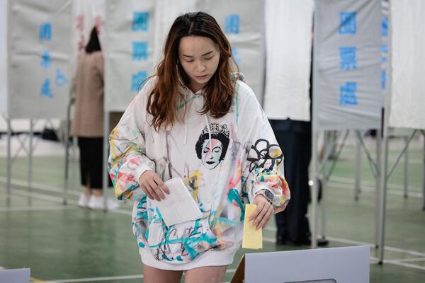 یک زن برای رای دادن به انتخابات ریاست جمهوری در یک شعبه رای گیری در دبیرستانی در تاینان رای می دهد. - اسپوتنیک ایران  