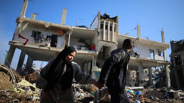 Палестинцы проходят мимо разрушенного здания в лагере беженцев Аль-Магази в центре сектора Газа - اسپوتنیک ایران  