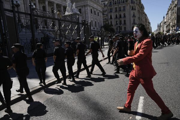 یک معترض با لباس جوکر در حالی که پشت سر پلیس راه می‌رود، منطقه نزدیک کنگره را در پایان اعتراض به اصلاحات اقتصادی و کارگری پیشنهادی دولت خاویر مایلی، رئیس‌جمهور آرژانتین، در جریان اعتصاب ملی در بوئنوس آیرس ترک می‌کند. 24 ژانویه 2024 - اسپوتنیک ایران  
