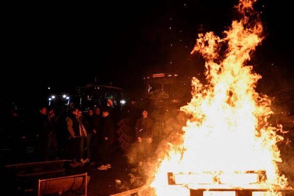 کشاورزان فرانسوی در حین تظاهرات در بزرگراه A6 در نزدیکی Chilly-Mazarin، در جنوب پاریس در کنار آتش ایستاده اند. - اسپوتنیک ایران  