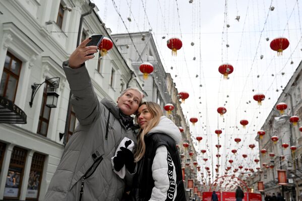 دختران در یکی از خیابان های مسکو که به افتخار جشن سال نو چینی تزئین شده است، عکس می گیرند. - اسپوتنیک ایران  