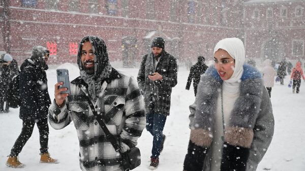 گردشگران هنگام بارش برف در مسکو در میدان سرخ قدم می زنند - اسپوتنیک ایران  