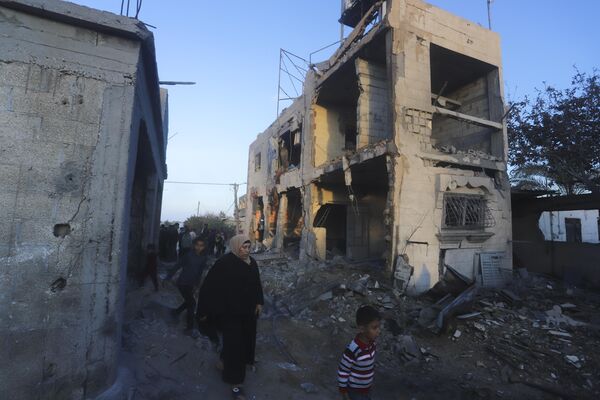فلسطینی ها از کنار ساختمان مسکونی ویران شده در حمله اسرائیل در رفح عبور می کنند.  - اسپوتنیک ایران  