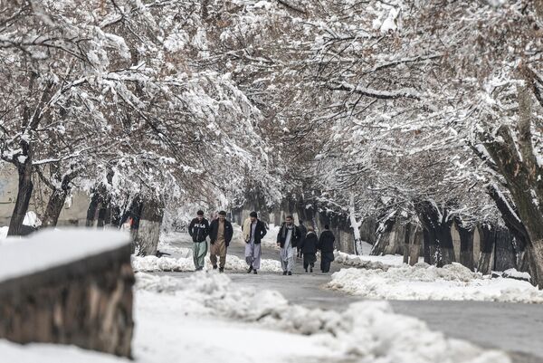 مردان افغان در تاریخ 19 فوریه 2024 در امتداد خیابان پر از برف در حومه کابل قدم می زنند. - اسپوتنیک ایران  