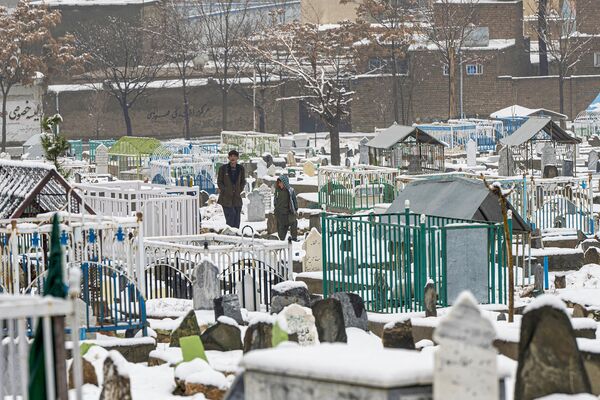 پسران افغان در 19 فوریه 2024 از یک قبرستان پر از برف در کابل عبور می کنند.  - اسپوتنیک ایران  