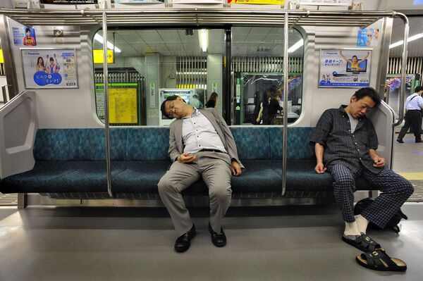 در 17 ژوئن 2008، دو مسافر در یک سفر درون شهری در خط راه آهن ژاپن (JR) سیستم قطار متروی توکیو خوابیده اند. - اسپوتنیک ایران  