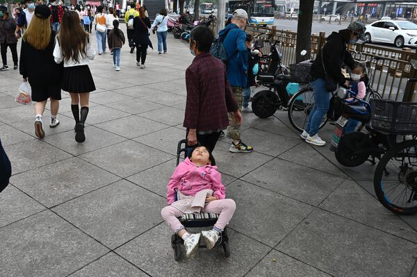 زنی در تعطیلات ملی &quot;هفته طلایی&quot; چین در پکن، کودکی را که خوابیده است بر روی چرخ دستیش حمل می کند.  2 اکتبر 2021 - اسپوتنیک ایران  