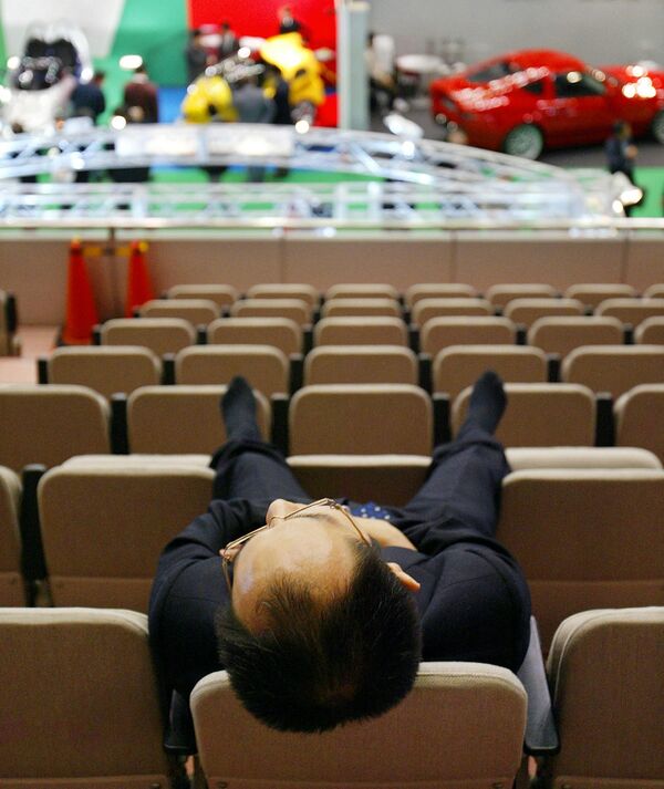 یک تاجر ژاپنی پیش از شروع  نمایشگاه خودروی توکیو در ماکوهاری، حومه توکیو، روی پشتی صندلی ها چرت می زند. 24 اکتبر 2003 - اسپوتنیک ایران  