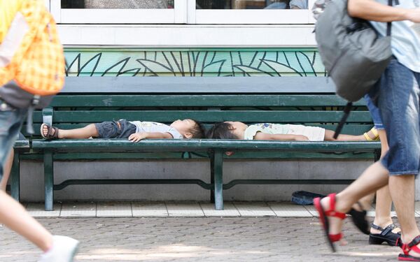 دو کودک روی نیمکتی در سایه در پارک تفریحی توشیمن در توکیو خوابیده اند. 28 ژوئیه 2007 - اسپوتنیک ایران  