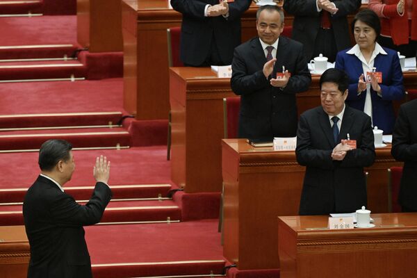 رهبر چین، شی جین پینگ هنگام ورود به جلسه افتتاحیه کنگره ملی خلق  در تالار بزرگ مردم در پکن در 5 مارس 2024 برای نمایندگان دست تکان می دهد. - اسپوتنیک ایران  