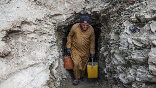 یک مرد افغان کانتینرهای پر از سنگ و خاک را از یک تونل در یک معدن طلا در کوه های یفتل سفلی ولایت بدخشان را از دل کوه بیرون می آورد - اسپوتنیک ایران  
