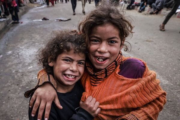 کودکان آواره فلسطینی در 14 مارس 2024، در میان نبردهای جاری بین اسرائیل و گروه شبه نظامی حماس، در اردوگاهی در کنار خیابانی در شهر رفح عکس می گیرند. درگیری اسرائیل و حماس که از 7 اکتبر آغاز شده است، منجر به تلفات انبوه غیرنظامیان شده، مناطق وسیعی را به یک زمین بایر پر از آوار تبدیل کرده و هشدارهایی را درباره قحطی قریب الوقوع در این سرزمین فلسطینی با جمعیت  2.4 میلیون نفر به دنبال داشته است. - اسپوتنیک ایران  
