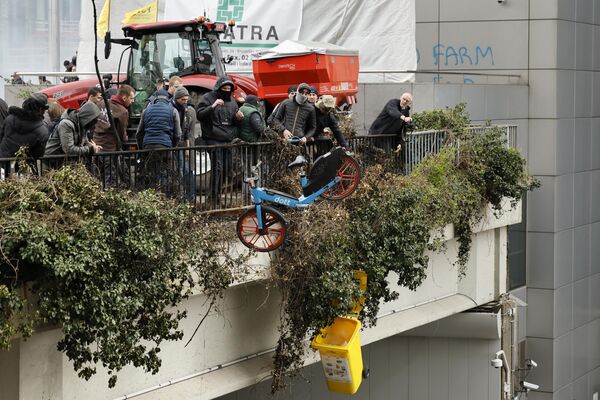 معترضان در طول تظاهرات کشاورزان در نزدیکی ساختمان شورای اروپا در بروکسل، سه شنبه، 26 مارس 2024، اشیایی را از روی یک پل هوایی کوچک پرتاب می کنند. ده ها تراکتور خیابان های نزدیک به مقر اتحادیه اروپا را مسدود کردند که وزیران کشاورزی 27 کشور عضو اتحادیه اروپا در آنجا نشستی برای بحث و گفتگو درباره بحران در بخش کشاورزی برگزاری می کنند که به ماه ها تظاهرات در کشورهای اروپایی منجر شده است. - اسپوتنیک ایران  
