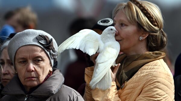 زنی کبوتر سفیدی را در مراسم ترحیم قربانیان حمله تروریستی به تالار کنسرت کروکوس سیتی در دست دارد - اسپوتنیک ایران  