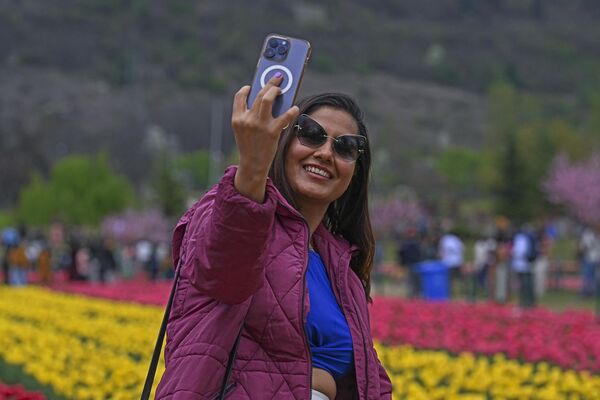یک گردشگر با تلفن همراه در باغ لاله یادبود ایندیرا گاندی در سرینگار در 3 آوریل 2024 سلفی می گیرد. - اسپوتنیک ایران  