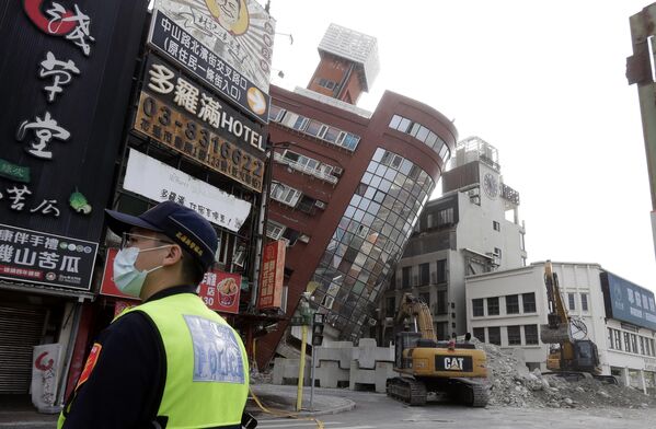 یک افسر پلیس یک روز پس از زلزله ای قدرتمند که شهر هوآلین در شرق تایوان چین را لرزاند، بیرون ساختمان نیمه فرو ریخته نگهبانی می کند. - اسپوتنیک ایران  