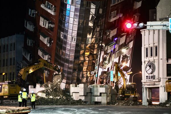 پرسنل اورژانس در 3 آوریل 2024 پس از زلزله بزرگی که شرق تایوان را لرزاند، در مقابل یک ساختمان نیمه فرو ریخته ایستاده اند. - اسپوتنیک ایران  