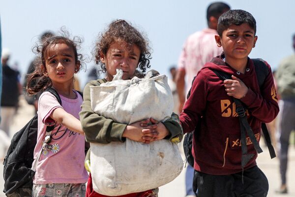 کودکان در بحبوحه درگیری ادامه دار در خاک فلسطین بین اسرائیل و گروه شبه نظامی حماس، در 14 آوریل 2024 از نصیرات در مرکز نوار غزه می گذرند، همراه با دیگر فلسطینی های آواره جاده ساحلی رشید را طی می کنند تا به شهر غزه بازگردند. - اسپوتنیک ایران  