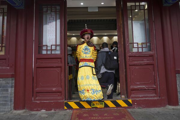 یک مغازه دار با لباسی از قرن گذشته  در یک فروشگاه سوغاتی نزدیک دیوار چین در حومه پکن. - اسپوتنیک ایران  