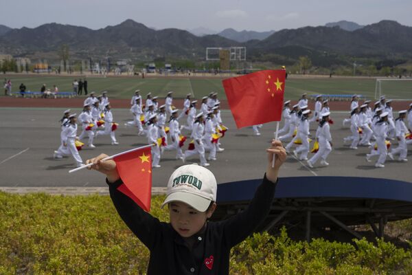 کودکی با پرچم در زمینه ملوانان چینی.به گفته روزنامه رسمی مردم چین، آکادمی بیش از 100000 افسر نیروی دریایی و ملوان را برای نیروی دریایی چین آموزش داده است و بیش از 80 درصد از کارکنان زیردریایی فارغ التحصیل شده یا در اینجا آموزش دیده اند. - اسپوتنیک ایران  