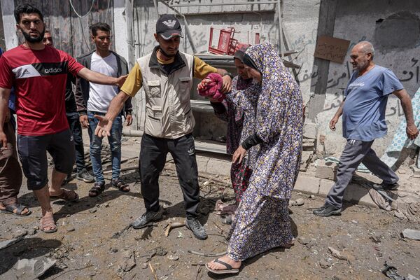 پس از حمله اسرائیل به اردوگاه البریج در مرکز نوار غزه در 22 آوریل 2024، در بحبوحه نبردهای جاری بین اسرائیل و گروه شبه نظامی حماس، یک زن فلسطینی زخمی قبل از انتقال به بیمارستان به سوی آمبولانس همراهی  می شود. - اسپوتنیک ایران  