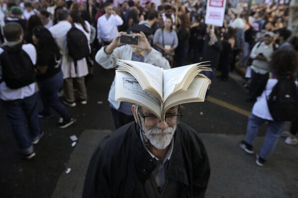 مردی کتاب به سر در رژه اعتراضی به بودجه دانشگاه در بوینس آیرس. - اسپوتنیک ایران  