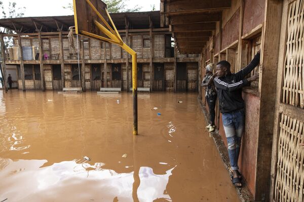 ساکنان محله فقیر نشین ماتاره از دیوار برای عبور از زمین مدرسه سیل زده به دنبال بارش شدید باران در پایتخت، نایروبی استفاده می کنند. - اسپوتنیک ایران  