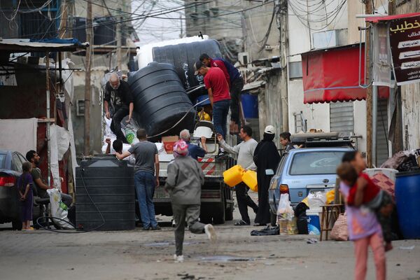فلسطینی ها در حالی که مردم از رفح در جنوب نوار غزه به مکان امن تر فرار می کنند، ظروف آب را در پشت یک کامیون بار می کنند. - اسپوتنیک ایران  