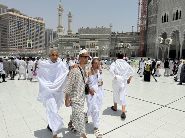 دو زائر نابینا در حین مراسم حج در مکه، عربستان سعودی، پنجشنبه، 13 ژوئن 2024، با کمک راهنمای خود در خارج از مسجد الحرام، مناسک حج را انجام می دهند. - اسپوتنیک ایران  