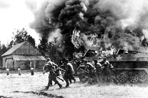 سربازان آلمانی نازی، با پشتیبانی نفربرهای زرهی، به سوی  یک روستای در حال سوختن روسیه  حرکت می کنند. 26 ژوئن 1941 - اسپوتنیک ایران  