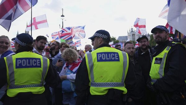 Police officers form a line in front of demonstrators from the Tommy Robinson-led Unite the Kingdom march and rally near Westminster, London, Saturday Sept. 13, 2025.  - اسپوتنیک ایران  