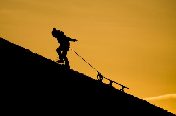 بچه ای در حال کشیدن سورتمه روی تپه برفی - اسپوتنیک ایران  