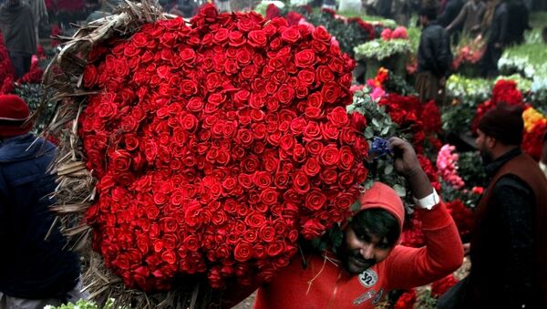 Разнорабочий несет букет красных роз на цветочном рынке в Лахоре, Пакистан - اسپوتنیک ایران  