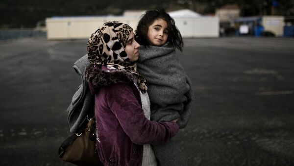 Женщина держит ребенка на руках в лагере беженцев в Греции - اسپوتنیک ایران  