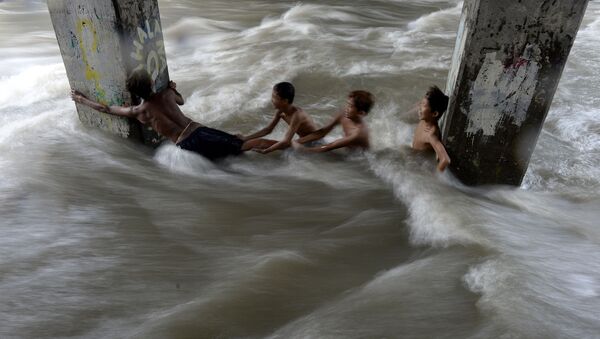 Дети в потоке воды под эстакадой во время наводнения на Филиппинах - اسپوتنیک ایران  