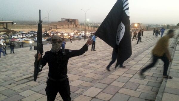 A fighter of Daesh, also known as ISIL, holds an ISIL flag and a weapon on a street in the city of Mosul, Iraq, in this June 23, 2014. - اسپوتنیک ایران  