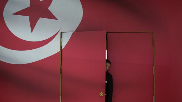A Tunisian guard looks out of the main gate of media center for its parliamentary election in Tunis, capital of Tunisia, on Oct. 25, 2014 - اسپوتنیک ایران  